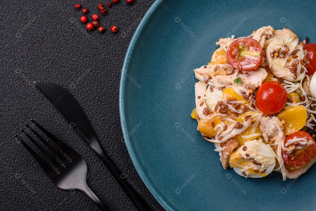 Deliciosa salada fresca com frango, ovos de codorna, tomate cereja, alface, sal e especiarias sobre fundo escuro de concreto