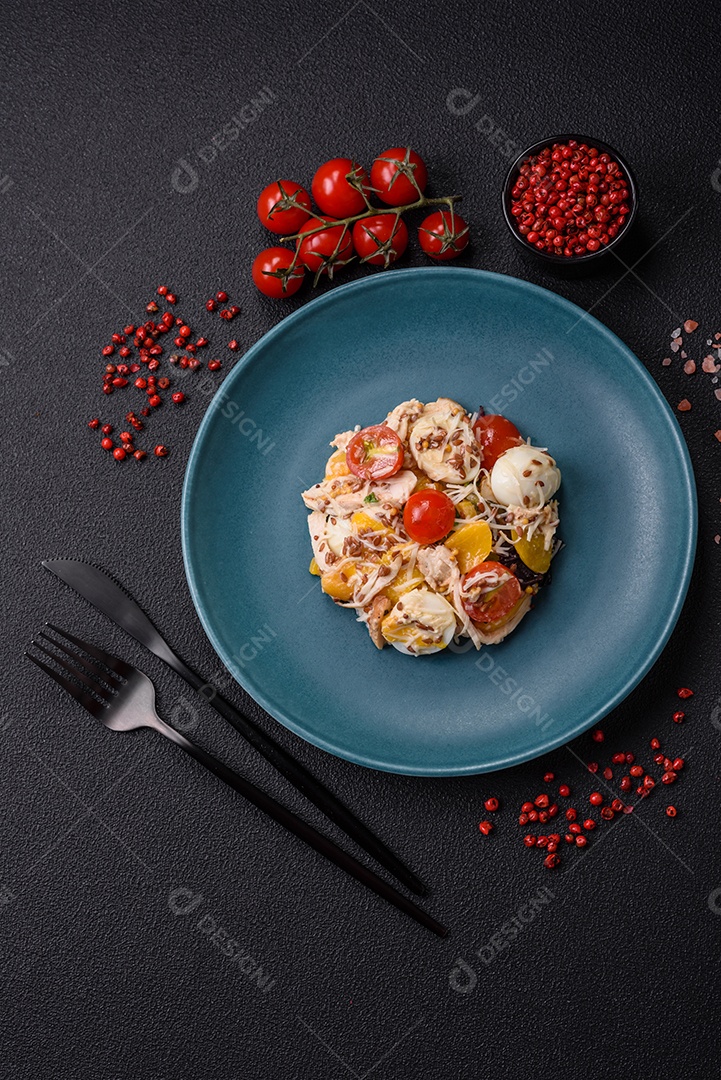 Deliciosa salada fresca com frango, ovos de codorna, tomate cereja, alface, sal e especiarias sobre fundo escuro de concreto