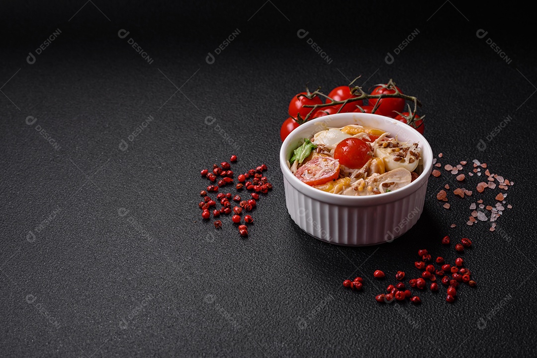 Deliciosa salada fresca com frango, ovos de codorna, tomate cereja, alface, sal e especiarias sobre fundo escuro de concreto
