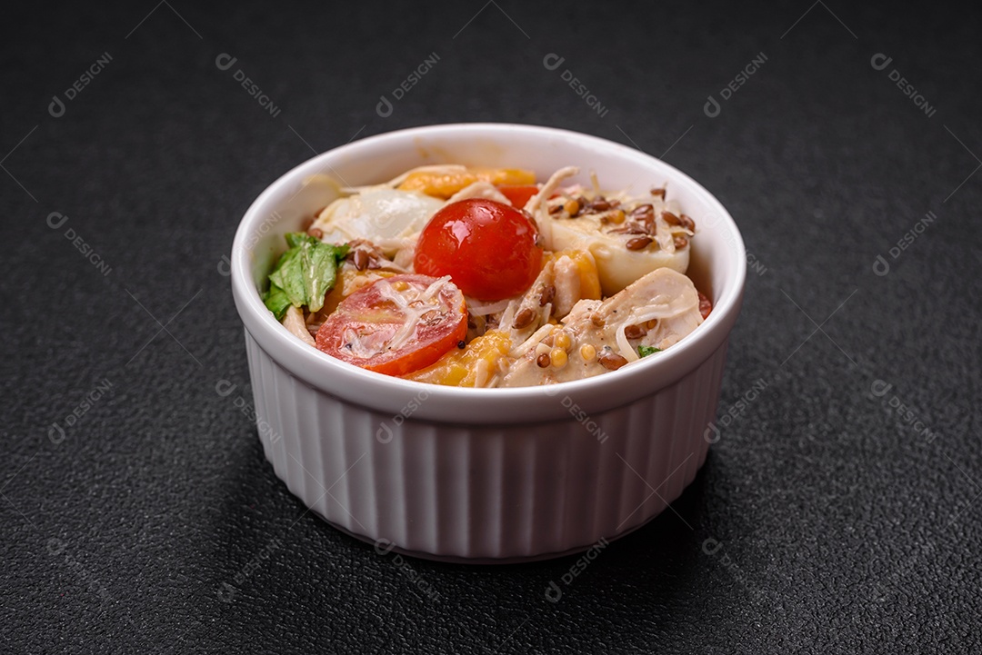 Deliciosa salada fresca com frango, ovos de codorna, tomate cereja, alface, sal e especiarias sobre fundo escuro de concreto