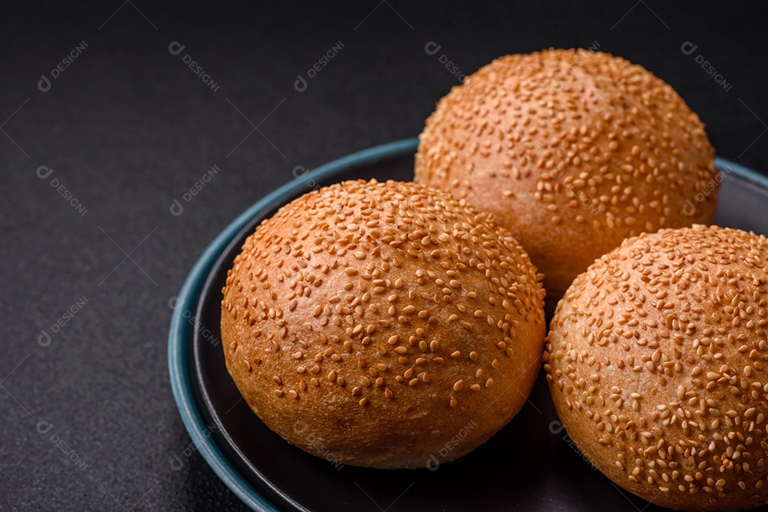 Delicioso pão redondo branco crocante fresco com sementes e grãos sobre um fundo escuro de concreto