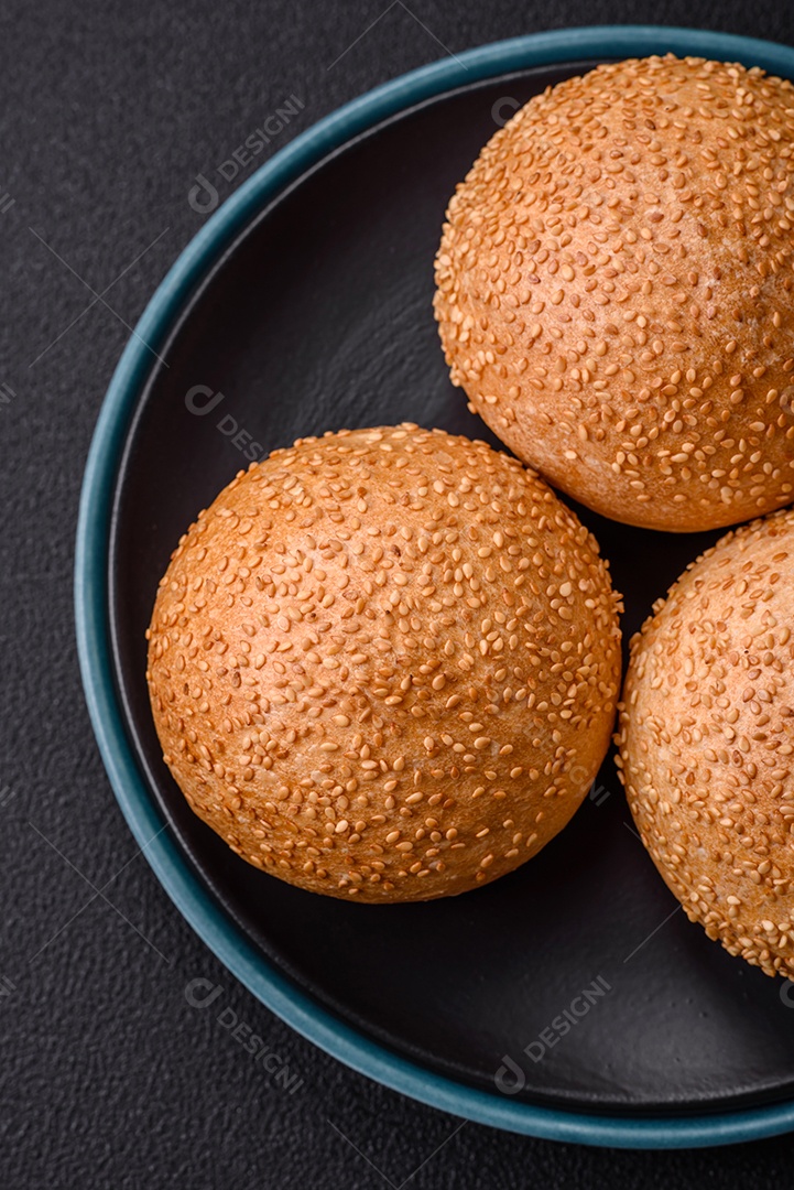 Delicioso pão redondo branco crocante fresco com sementes e grãos sobre um fundo escuro de concreto