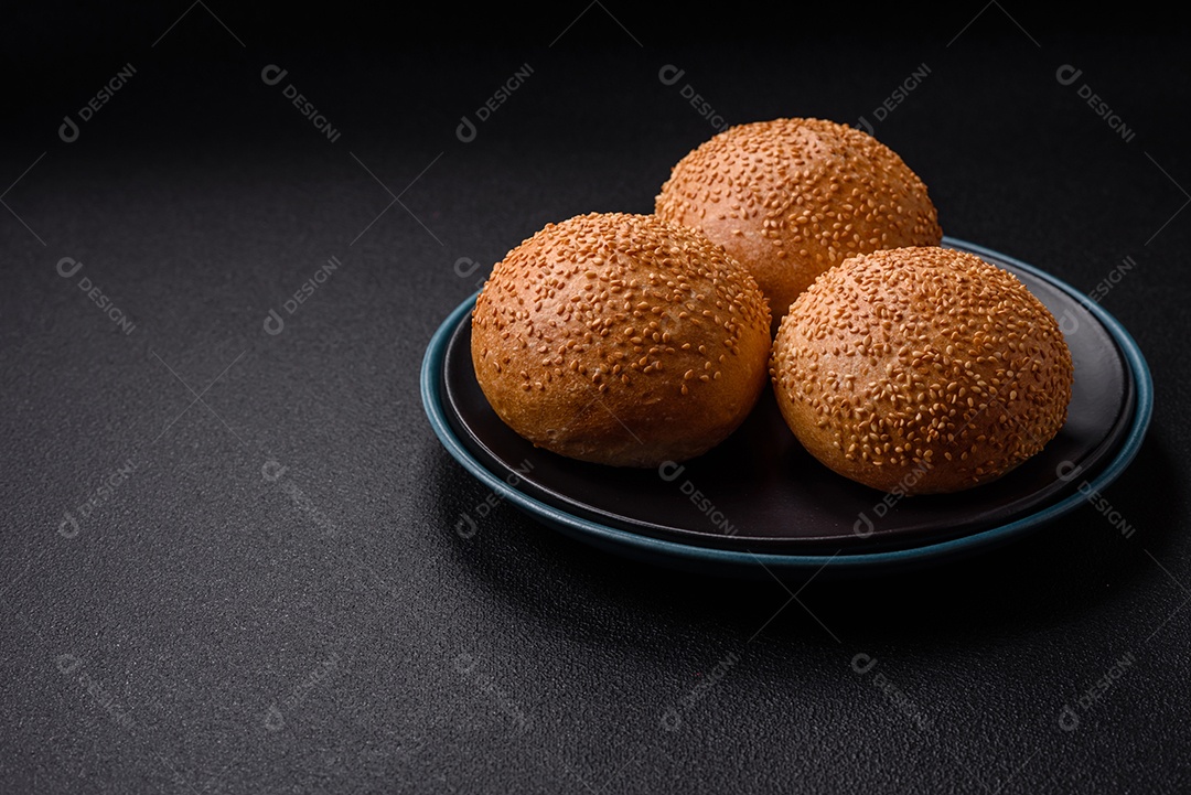 Delicioso pão redondo branco crocante fresco com sementes e grãos sobre um fundo escuro de concreto