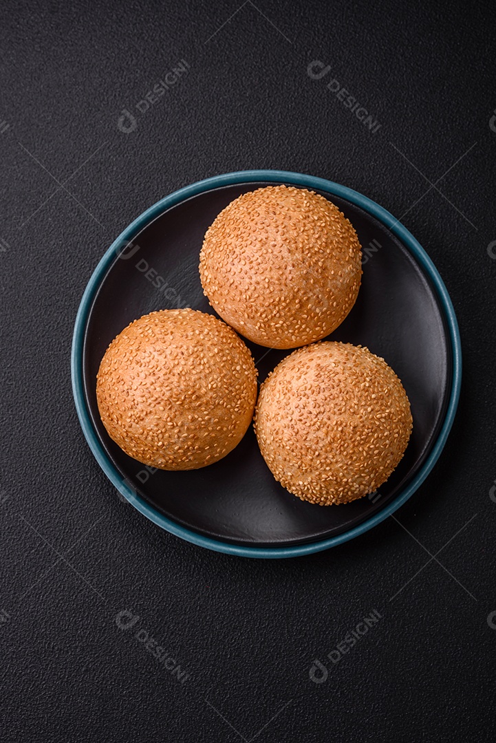 Delicioso pão redondo branco crocante fresco com sementes e grãos sobre um fundo escuro de concreto