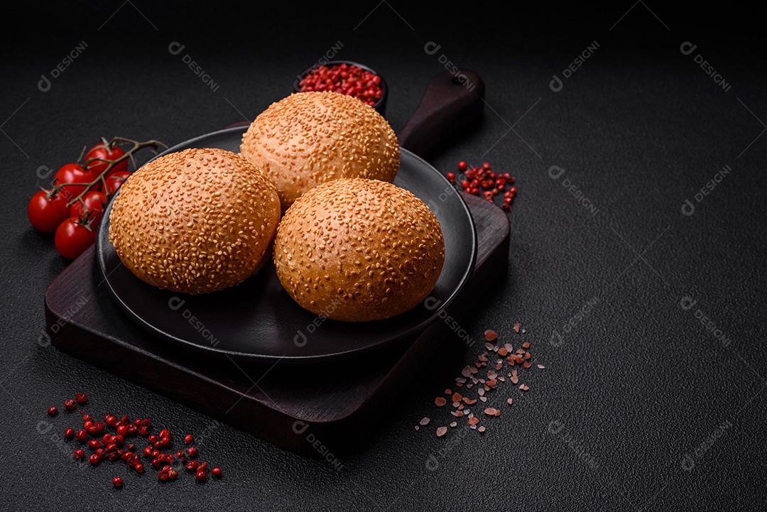 Delicioso pão redondo branco crocante fresco com sementes e grãos sobre um fundo escuro de concreto