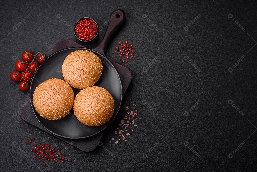 Delicioso pão redondo branco crocante fresco com sementes e grãos sobre um fundo escuro de concreto