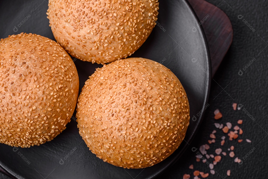 Delicioso pão redondo branco crocante fresco com sementes e grãos sobre um fundo escuro de concreto