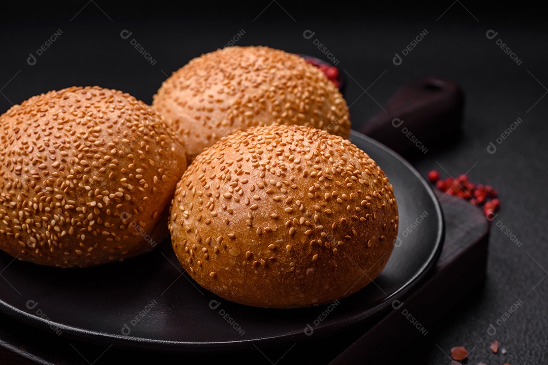Delicioso pão redondo branco crocante fresco com sementes e grãos sobre um fundo escuro de concreto