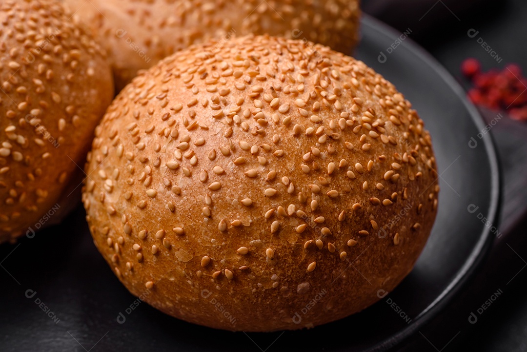 Delicioso pão redondo branco crocante fresco com sementes e grãos sobre um fundo escuro de concreto