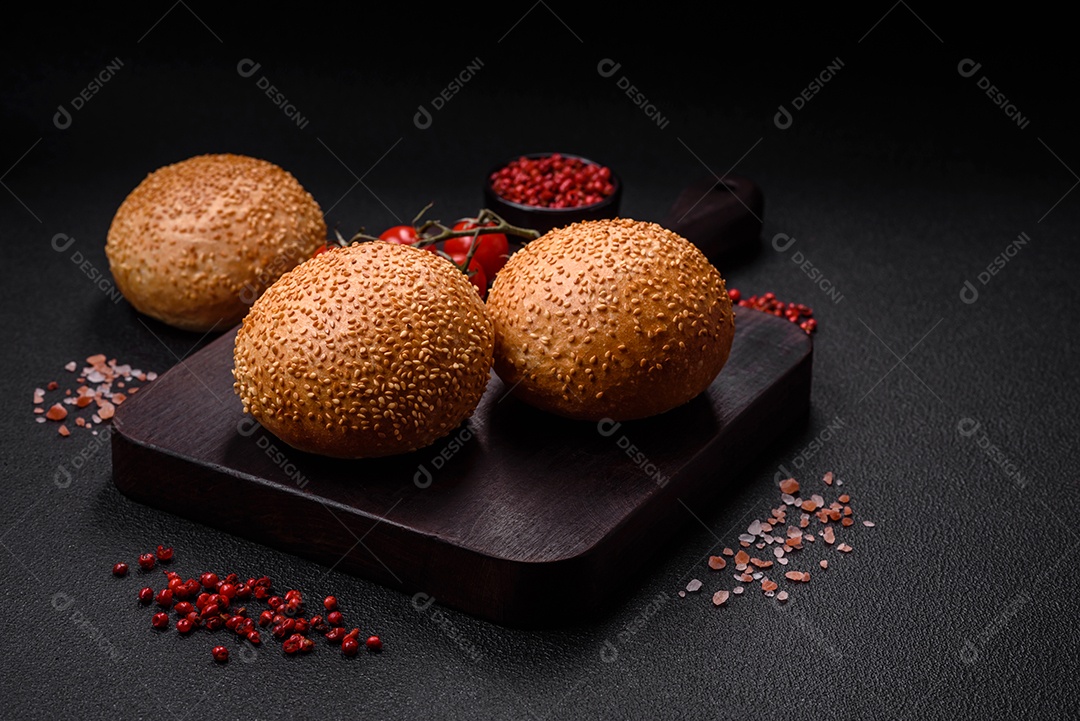 Delicioso pão redondo branco crocante fresco com sementes e grãos sobre um fundo escuro de concreto