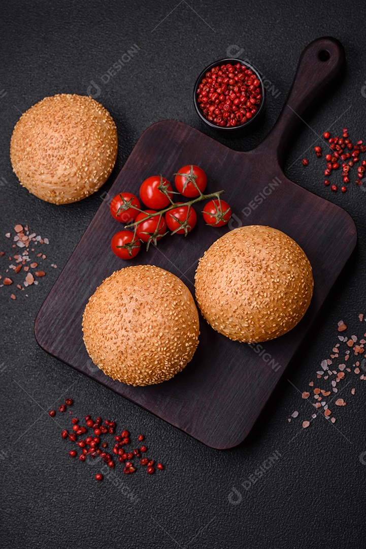 Delicioso pão redondo branco crocante fresco com sementes e grãos sobre um fundo escuro de concreto