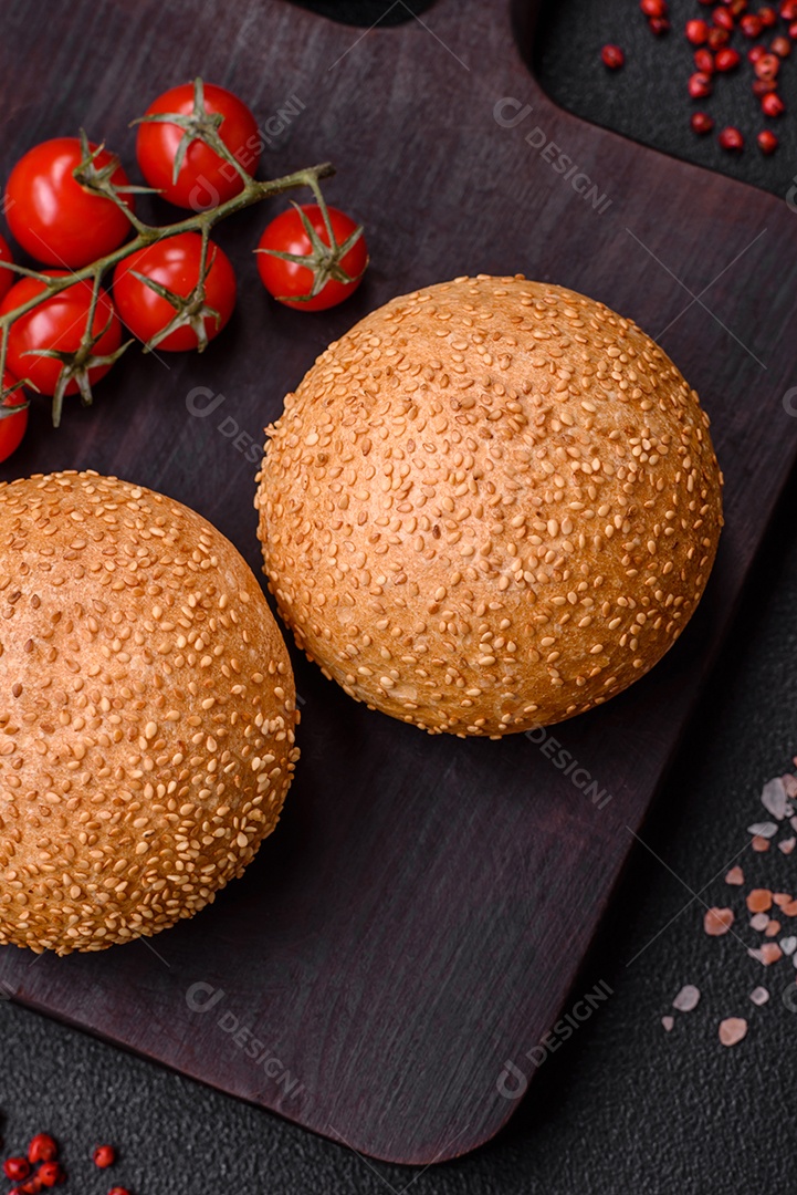 Delicioso pão redondo branco crocante fresco com sementes e grãos sobre um fundo escuro de concreto