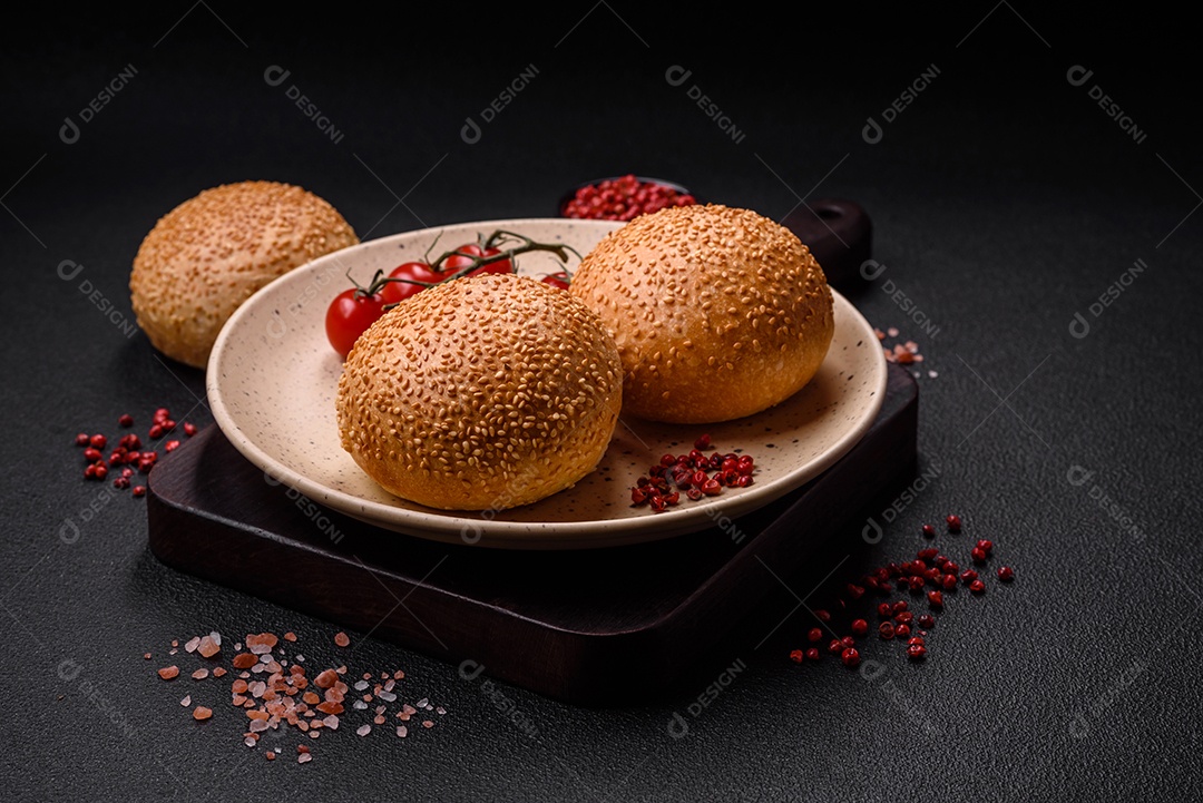 Delicioso pão redondo branco crocante fresco com sementes e grãos sobre um fundo escuro de concreto