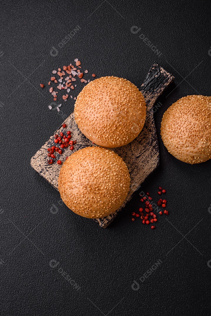 Delicioso pão redondo branco crocante fresco com sementes e grãos sobre um fundo escuro de concreto