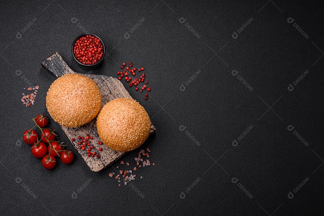 Delicioso pão redondo branco crocante fresco com sementes e grãos sobre um fundo escuro de concreto