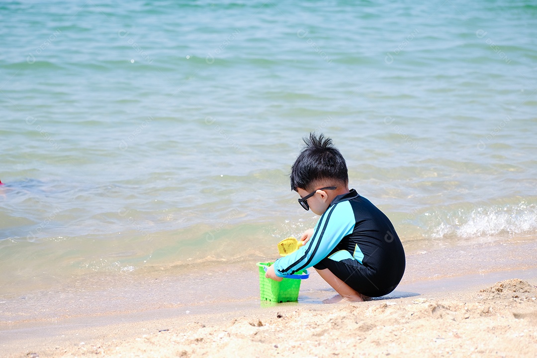Garotinho brincando na areia da praia