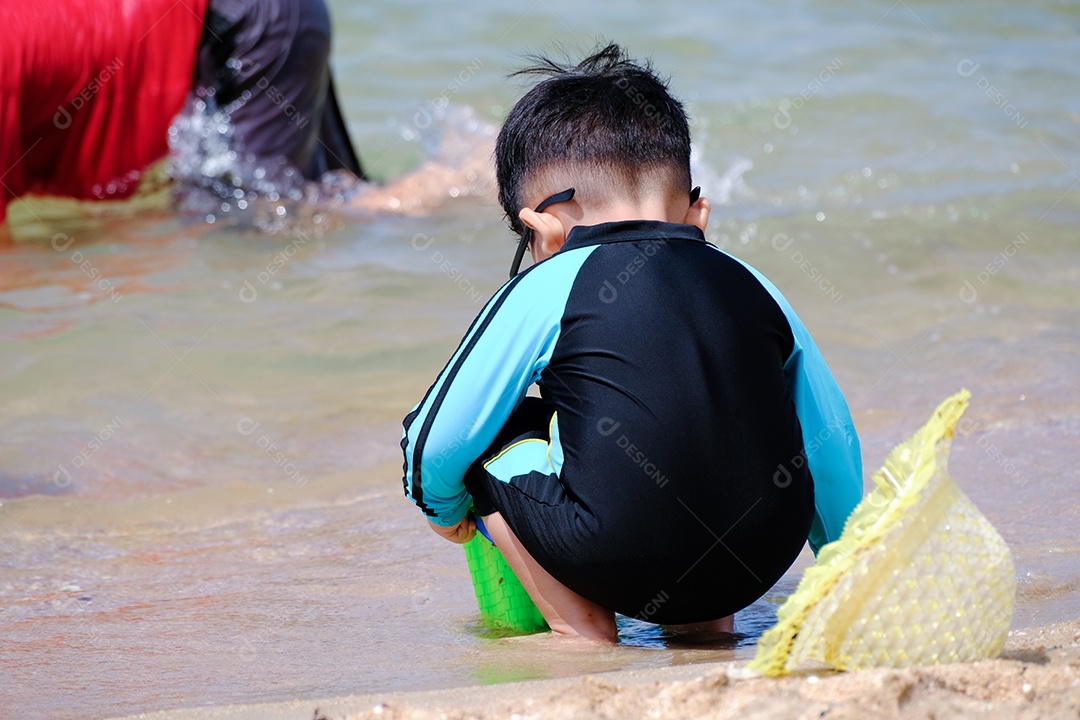 Garotinho brincando na areia da praia
