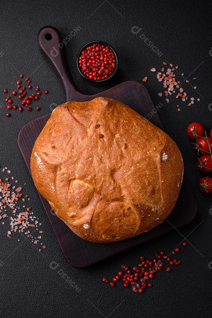 Delicioso pão integral crocante fresco com sementes e grãos sobre um fundo escuro de concreto