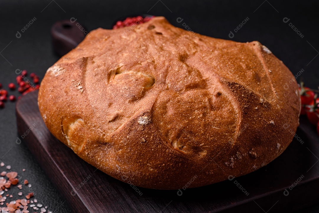 Delicioso pão integral crocante fresco com sementes e grãos sobre um fundo escuro de concreto