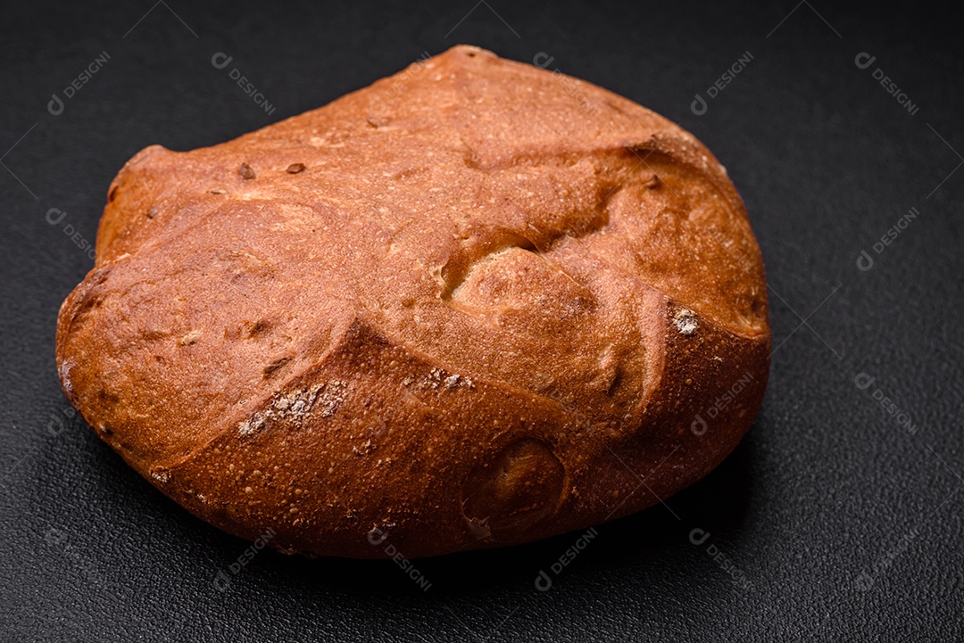 Delicioso pão integral crocante fresco com sementes e grãos sobre um fundo escuro de concreto