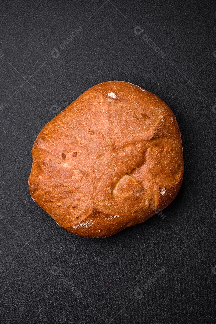 Delicioso pão integral crocante fresco com sementes e grãos sobre um fundo escuro de concreto