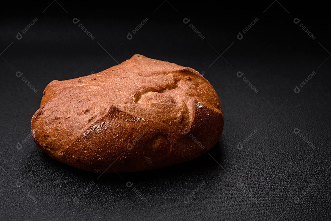Delicioso pão integral crocante fresco com sementes e grãos sobre um fundo escuro de concreto