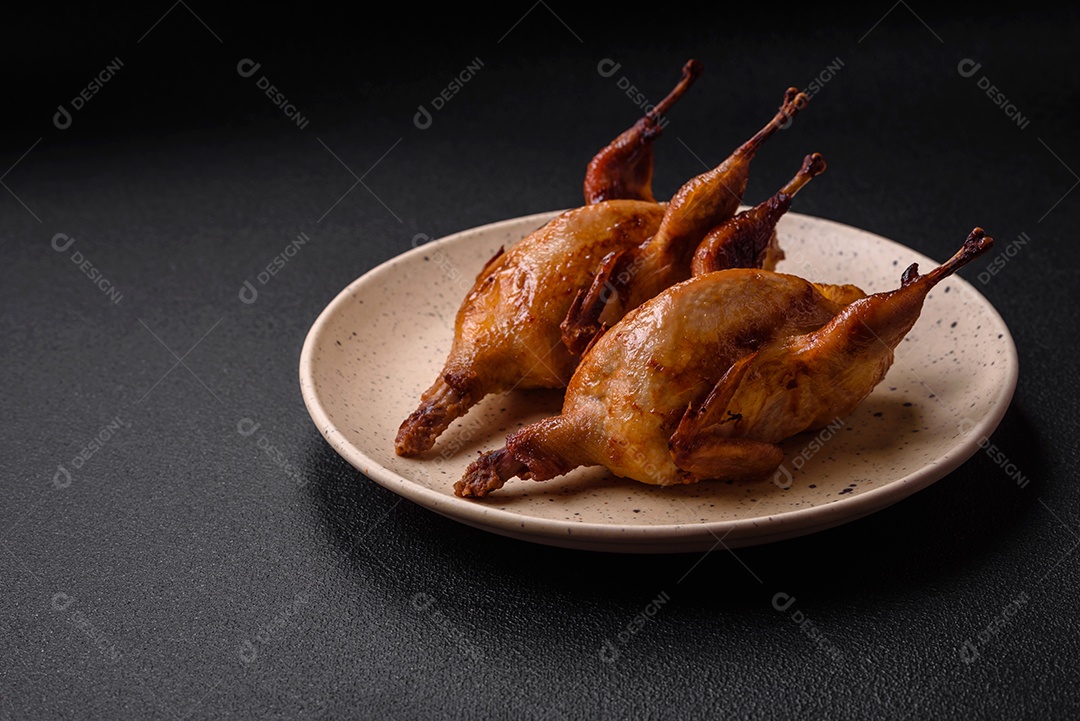 Codorna assada, perdiz ou pombo recheado com laranja com especiarias e ervas sobre fundo escuro de concreto