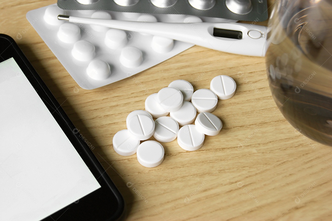 Remédios termômetros e copo com água