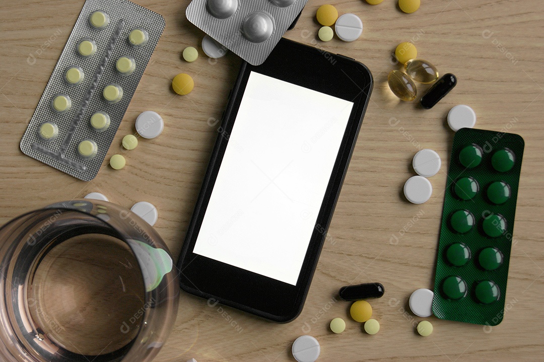 Diversos comprimidos e cartelas de remédio com termômetro sobre mes de madeira