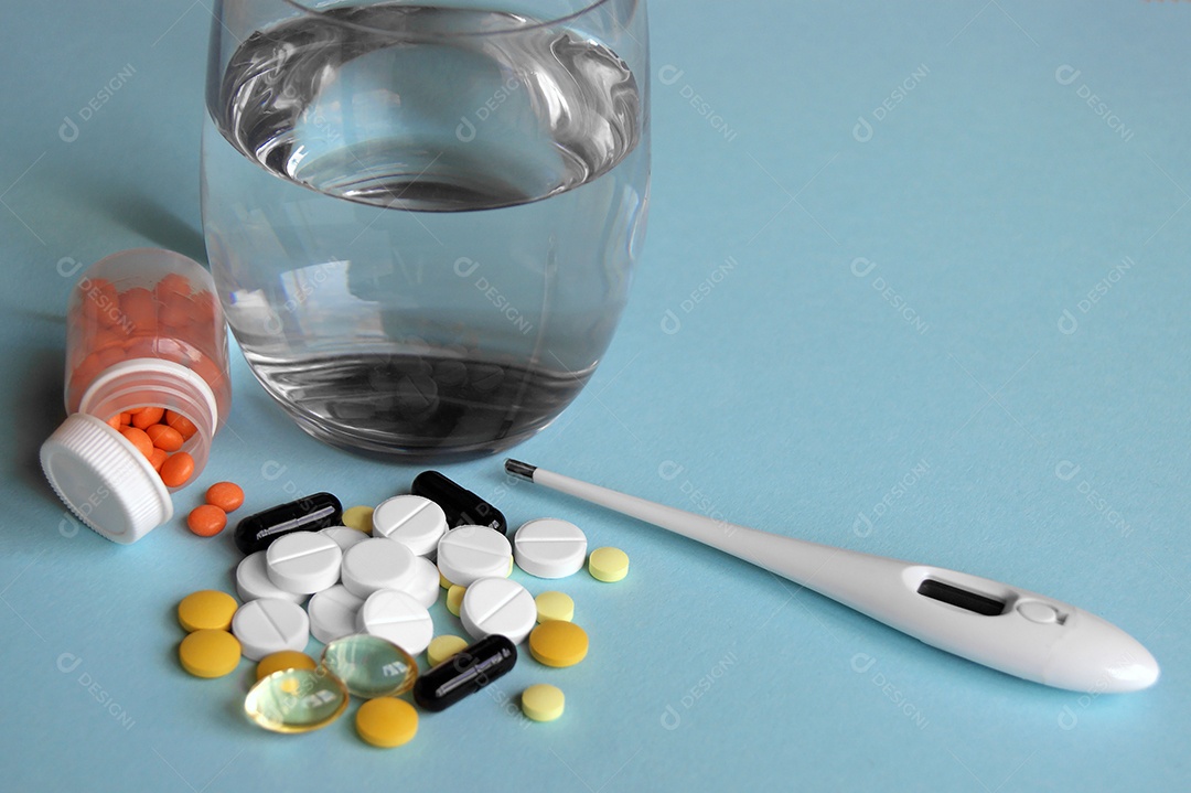 Copo de água e vários remédios com termômetro em fundo azul