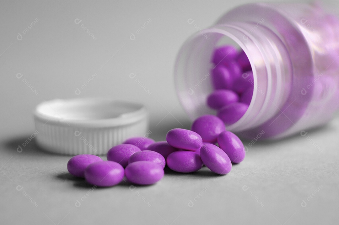 Frasco de cápsulas de medicamentos caído sobre fundo cinza