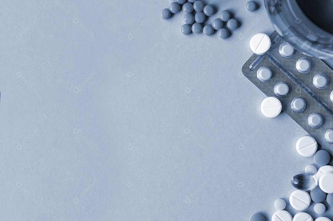 Vários comprimidos e cartela de remédio sobre fundo cinza