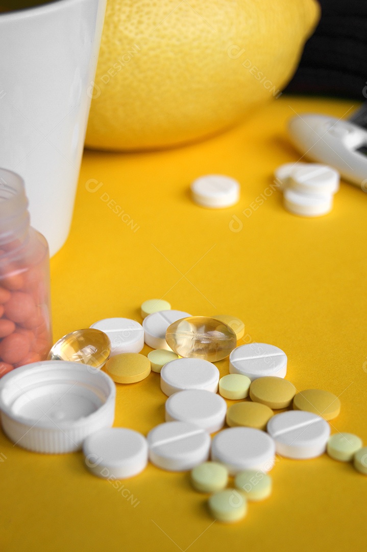 Diversos comprimidos, comprimidos e cápsulas de medicamentos farmacêuticos em fundo amarelo.