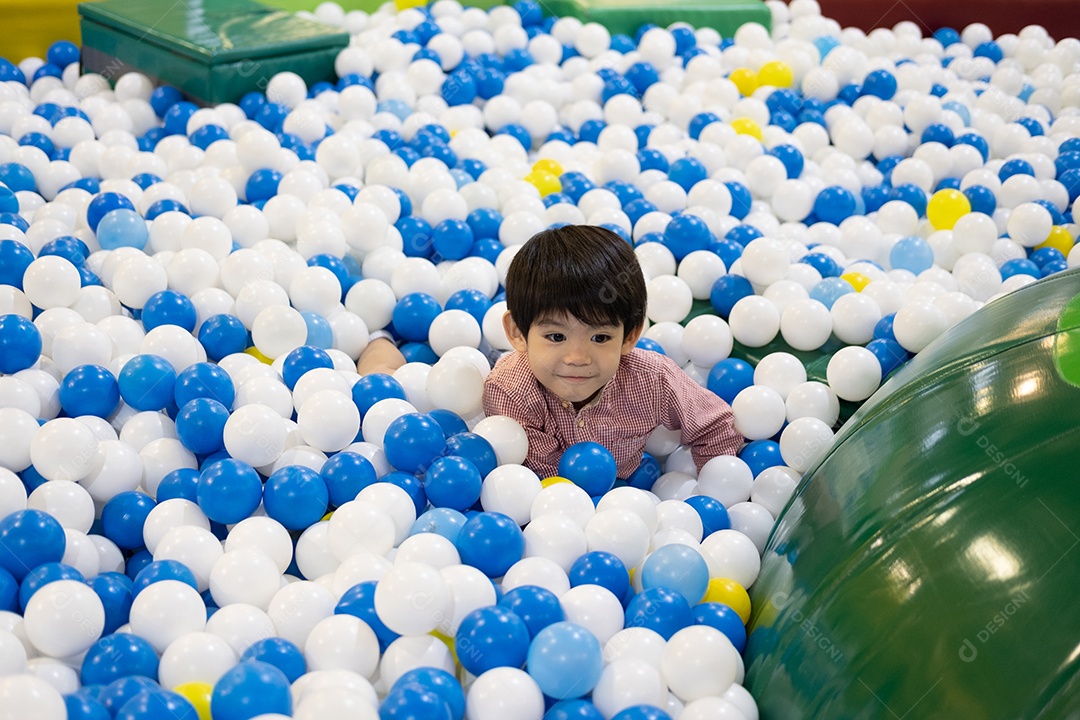 Um garotinho asiático brincava de esconde-esconde entre as bolas