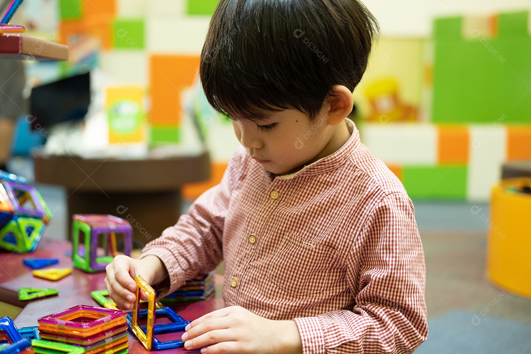 Menino asiático brincando com carro de brinquedo no parque infantil