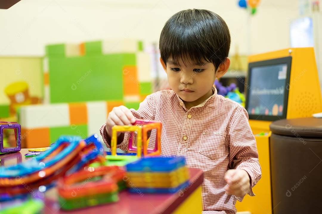 Menino asiático brincando com brinquedos no parque infantil