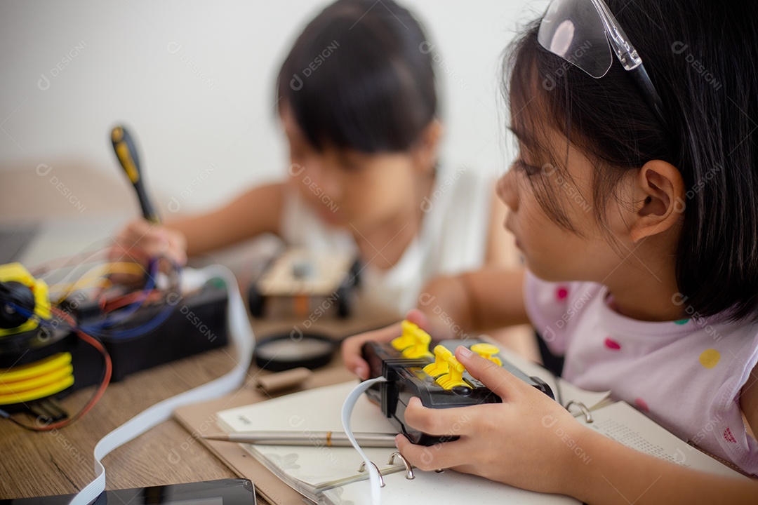 Crianças criativas aprendem em casa codificando carros-robôs e cabos de placas eletrônicas em STEM.