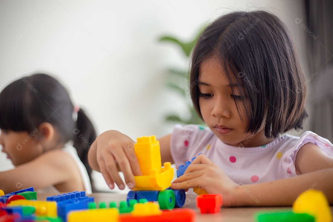 Crianças criativas aprendem em casa codificando carros-robôs e cabos de placas eletrônicas em STEM. Adorável menina jogando blocos de brinquedo em uma sala iluminada