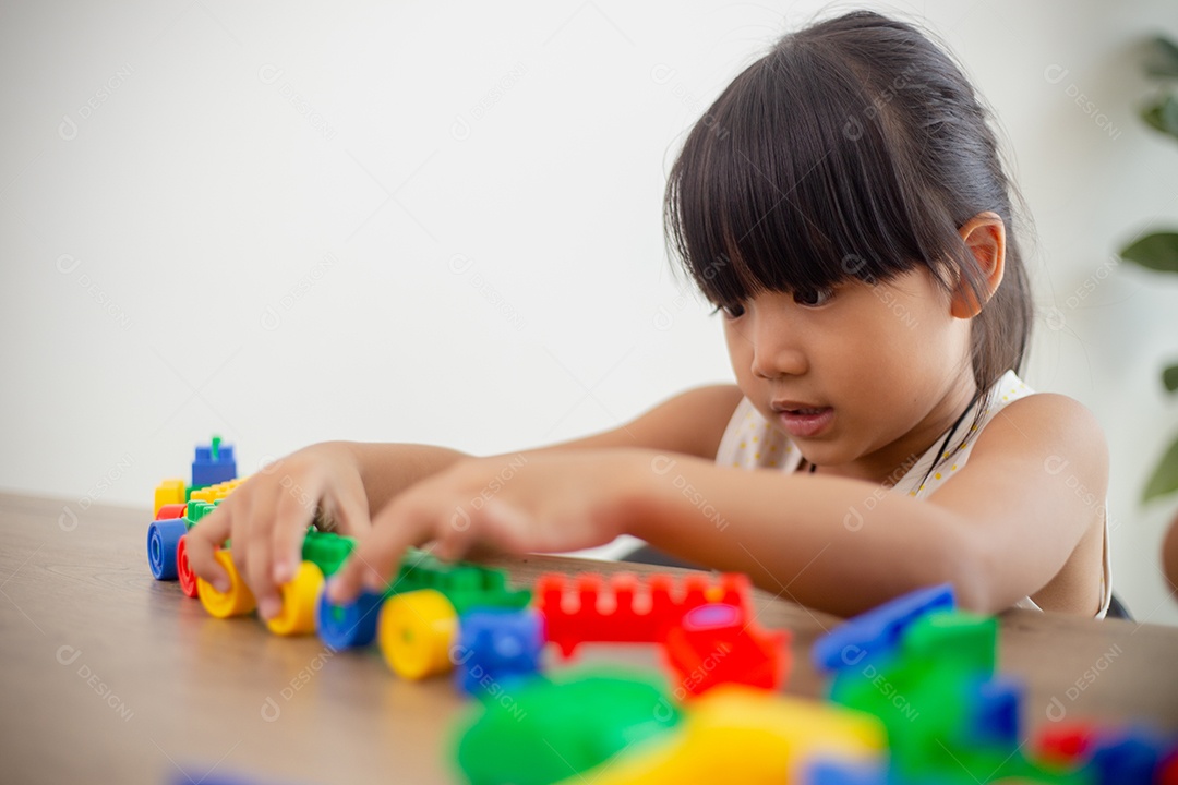 Adorável menina jogando blocos de brinquedo em uma sala iluminada