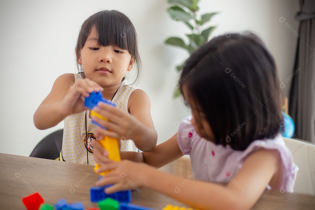 Adorável menina jogando blocos de brinquedo em uma sala iluminada