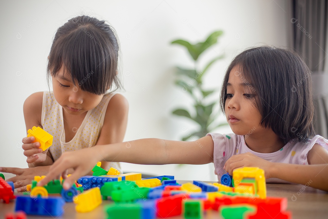 Adorável menina jogando blocos de brinquedo em uma sala iluminada