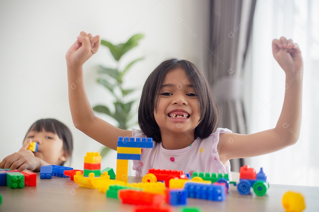 Adorável menina jogando blocos de brinquedo em uma sala iluminada