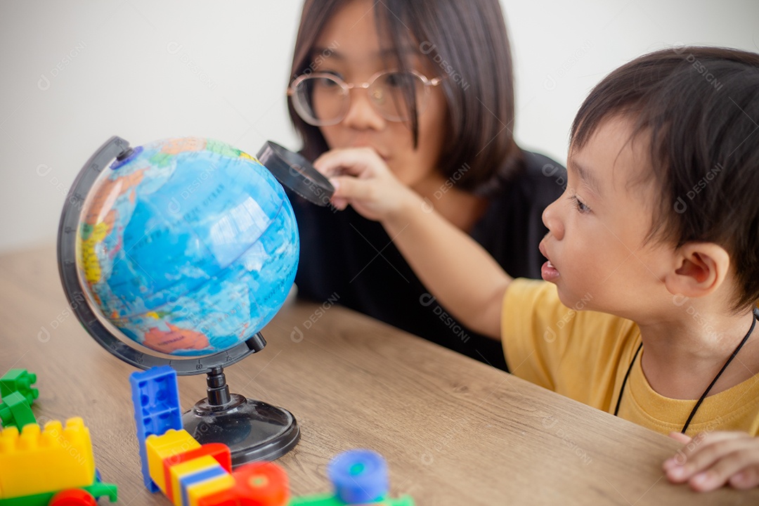 Irmão e irmã asiáticos brincam com um designer de blocos de brinquedo na mesa da sala de estar em casa.