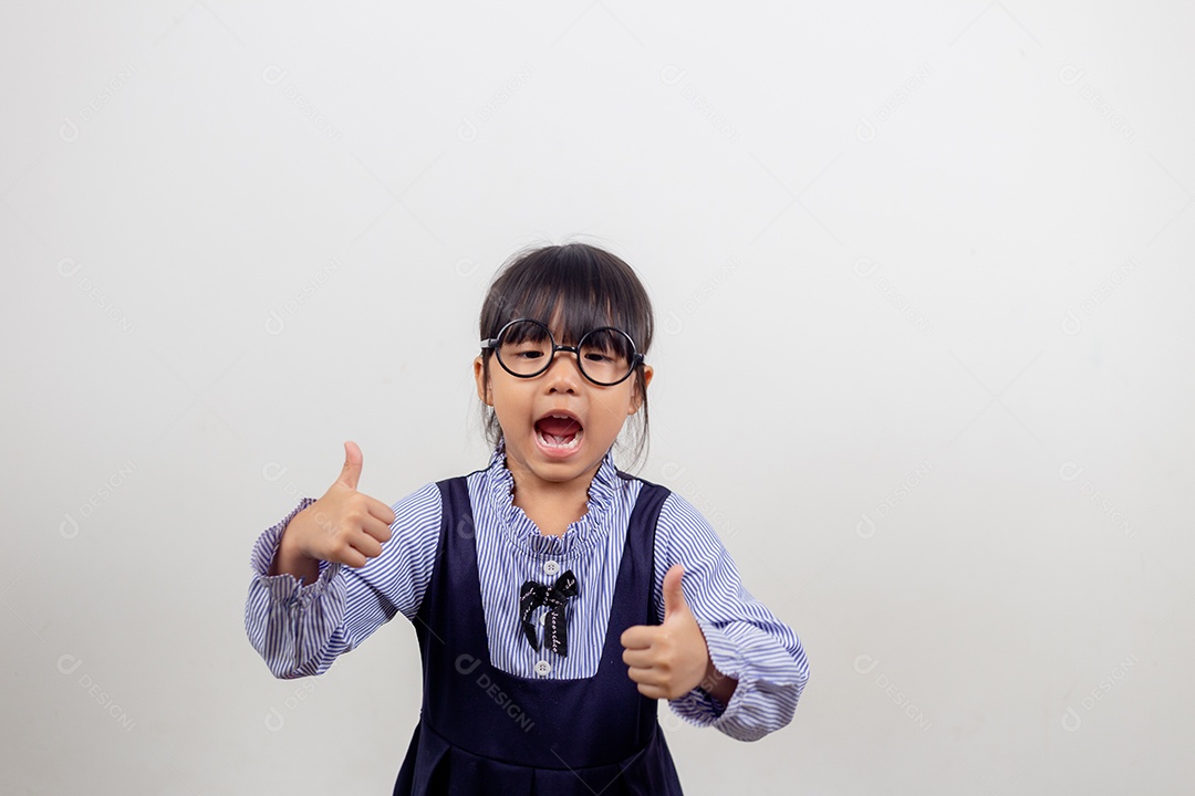 Linda menina pré-escolar isolada no fundo cinza do estúdio usa óculos olha para a câmera