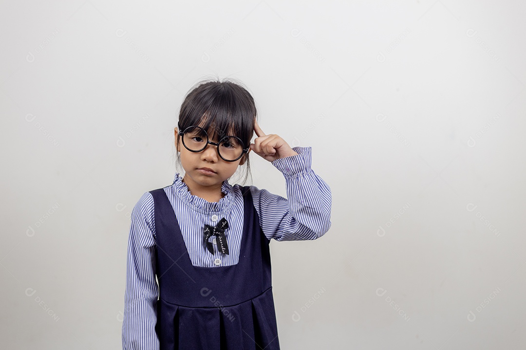 Linda menina pré-escolar isolada no fundo cinza do estúdio usa óculos olha para a câmera