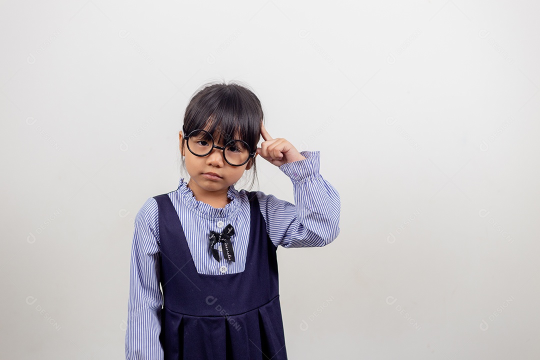 Linda menina pré-escolar isolada no fundo cinza do estúdio usa óculos olha para a câmera