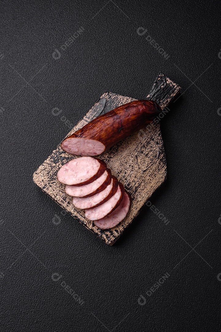 Deliciosa salsicha defumada com sal e especiarias cortadas em fatias sobre um fundo escuro de concreto