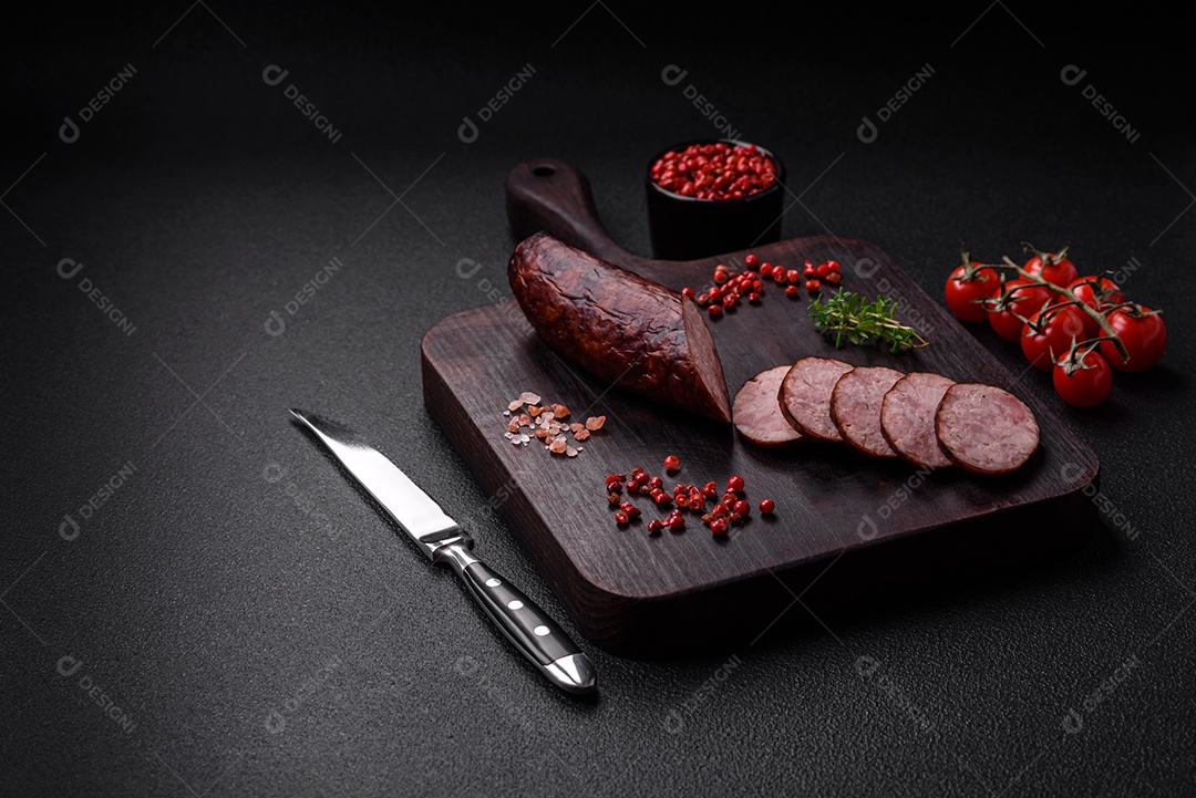 Deliciosa salsicha defumada com sal e especiarias cortadas em fatias sobre um fundo escuro de concreto