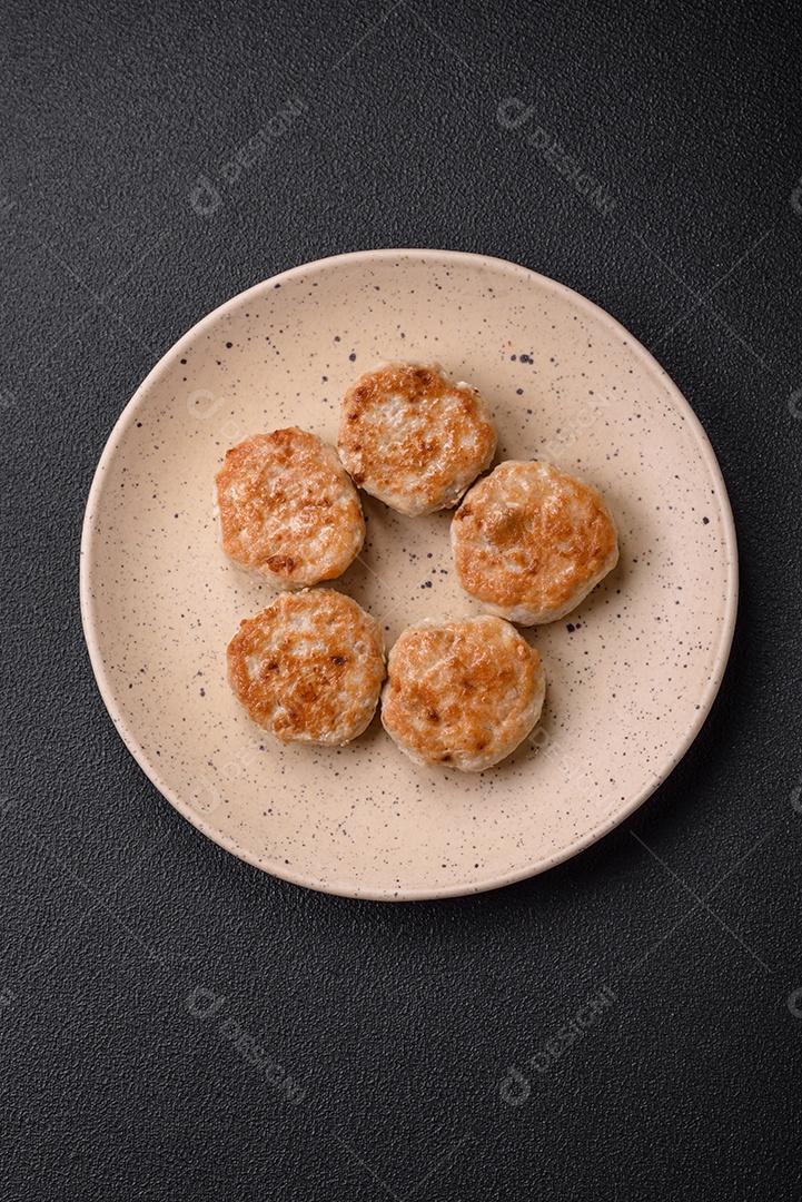 Almôndegas fritas de carne picada, carne de porco ou frango com sal, especiarias e ervas sobre um fundo escuro de concreto