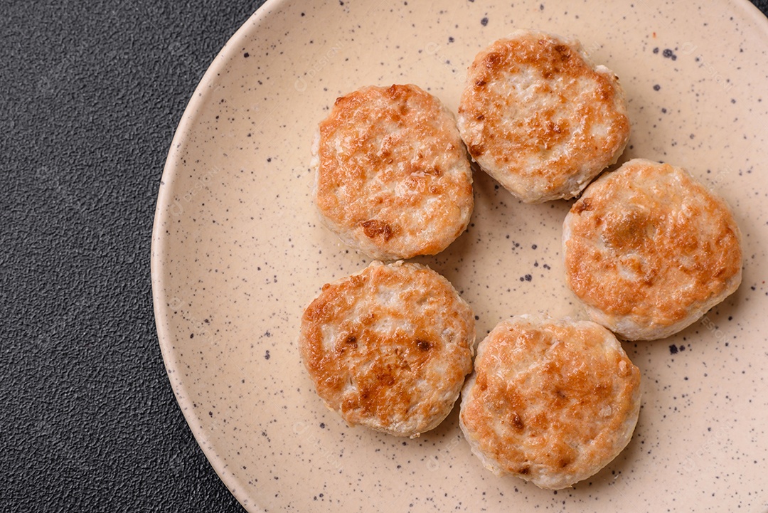 Almôndegas fritas de carne picada, carne de porco ou frango com sal, especiarias e ervas sobre um fundo escuro de concreto